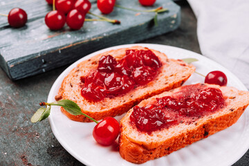 Fresh  ripe cherries on the  wooden desk and  bread with delicious jelly