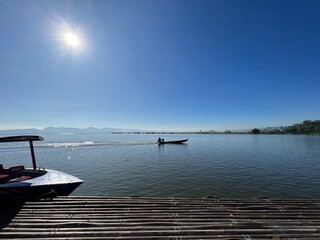 Beautiful Calm Water Reflection Lake and Fisherman working fishing on Boats with Blue Sky and Sunny Weather Clear Horizon