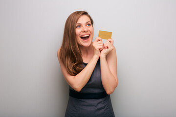 Happy business woman in gray dress with credit card looking side away. isolated female business person portrait with mouth open and positive emotion.