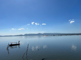 Beautiful Calm Water Reflection Lake and Fisherman working fishing on Boats with Blue Sky and Sunny Weather Clear Horizon