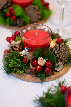 Vertical photo Christmas red candle composition with fir-tree branch decorated with berries. Concept: table setting for the Christmas holiday Christmas decorations cozy home 