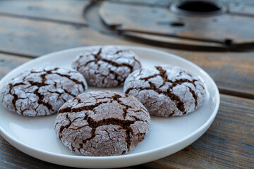 Homemade almond cookies with cocoa sprinkled with powdered sugar on a plate on a wooden background. High-quality photo