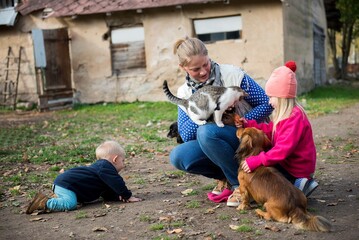 Mom and children are happy and hugging lots pets in the yard of the farm