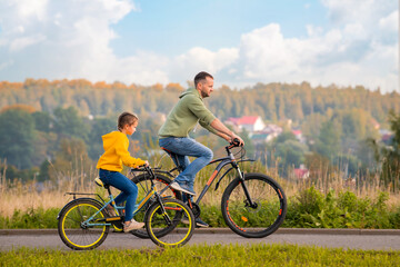 Fototapeta na wymiar Happy father and daughter take bike ride in nature in autumn.