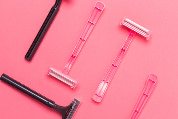 Naklejka premium Shaving Concepts. Upper Flat-Lay Image of Various Women's Colorful Pink and Black Disposable Razors Shavers Placed in Different Directions On Pink Coral Background.