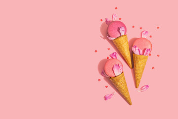 Ice cream waffle cones with macarons on pink background. Sweet dessert, summer concept