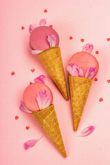 Ice cream waffle cones with macarons on pink background. Sweet dessert, summer concept