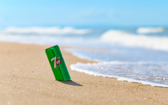 Anapa, Russia - July 2022: A can of 7 Up drink on the sandy seashore against the backdrop of waves. Selective focus on a can of drink.