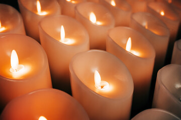 Candles burning brightly. Modern memorial candle on batteries in church. Abstract background