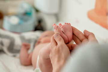 Obraz na płótnie Canvas Men's hands hold the small legs of a newborn baby
