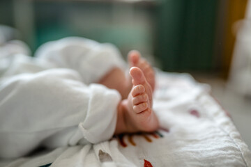 Small children's feet are lying on the bedspread. Cute newborn concept