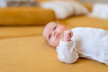 Funny kid lies on a yellow sofa and pokes his fist at the camera, the focus is on a small cam