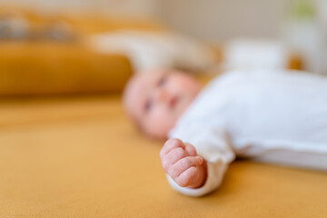 Funny kid lies on a yellow sofa and pokes his fist at the camera, the focus is on a small cam