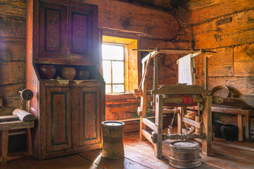 Antique furniture and household items in a rustic log house built in the 19th century. The interior of an old house. Dark log walls of the house. Rustic architecture.