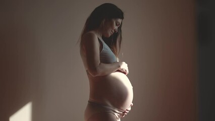 pregnant woman. health pregnancy motherhood procreation concept. close-up belly of a pregnant woman. woman waiting for a newborn baby. pregnant woman holding her belly sun indoors - Powered by Adobe