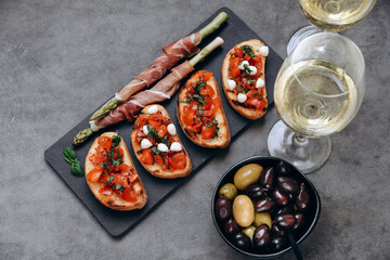 Snacks in the restaurant bruschetta with tomatoes and asparagus with prosciutto and olives two...