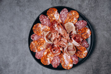 Salami on a black plate and olives and r white wine or Prosecco in a restaurant aperitif meal