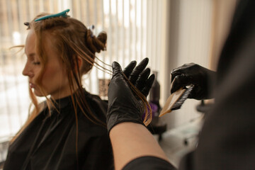 
Close-up of female hands holding the hair rows in professional hairstyles salon. The hairdresser...