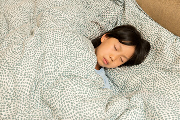 暖かい布団の中で寝ている小学生の女の子の様子