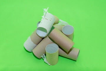 A pile of empty toilet paper tubes on a green background. The concept is a global crisis and a lack of things to meet basic needs.