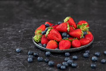 strawberries and blueberries on black background