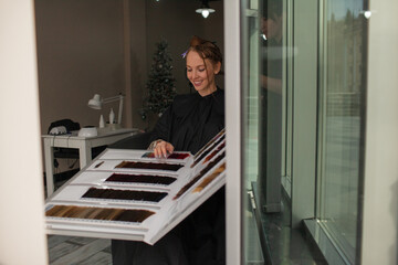 
Close-up of female hands holding the paint color palettes in professional hairstyles salon. The hairdresser paints or makes keratin, haircuts to a girl in a professional salon