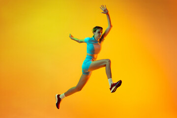 Fototapeta na wymiar Professional longjumper. One female athlete in sports uniform jumping isolated on yellow background. Concept of sport, action, motion, speed.