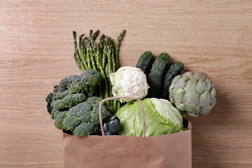 Bunch of mixed vegetables, herbs and greens in a brown paper bag. Vegan diet products. Clean eating concept. Eco friendly bag full of groceries. Close up, copy space, background, top view, overhead