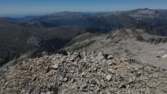Circular drone footage of people on the Aneto summit in the Pyrenees mountains.