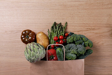 Bunch of mixed vegetables, herbs and greens in a brown paper bag. Vegan diet products. Clean eating concept. Eco friendly bag full of groceries. Close up, copy space, background, top view, overhead
