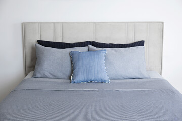 Hotel room with freshly made king sized bed with headboard, perfectly clean and ironed sheets, puffy pillows in natural sun light. Kingsize bed in a furniture showroom. Close up, copy space for text.