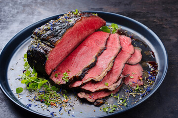 Traditional Commonwealth Sunday roast as sliced cold cuts roast beef with herbs and spice as close-up on a design plate