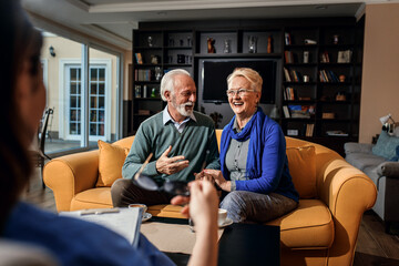 Female nurse talking to senior couple at nursing home.