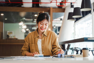 Young Asian businesswoman freelancer doing accounting tax analysis report and working her job on computer tablet in modern office.