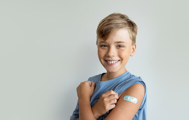 Child after vaccination with a adhesive band-aid patch arm bandage to prevent any infection over white background. Positive concept of healthy lifestyle and care. - obrazy, fototapety, plakaty