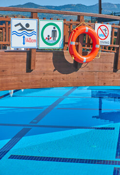 Lifebuoy, pool dept and no diving signs next to each other