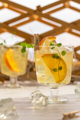 Two glasses full of fresh citrus lemonade with cocktail straw and slices of orange, mint leaves. Summer drink with ice. vertical position.