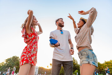 company of friends having fun together in park listening to music