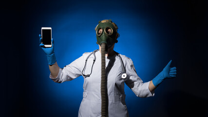 doctor woman in a gas mask shows thumb up and holds a mobile phone in her hand on a blue background