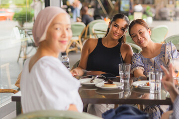 Happy lady having coffee and cake together at cafe outdoors.