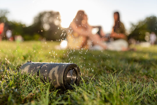 wireless waterproof speaker of friends having fun together in park listening to music