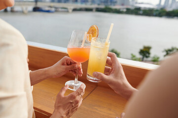 Fototapeta premium Hands of young people toasting with cocktails glasses at rooftop party