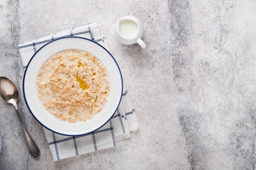 Oatmeal. Bowl of oatmeal porridge with strawberry, almond and milk on vintage light grey teal table. Top view in flat lay style. Natural ingredients. Hot and healthy breakfast and diet food.