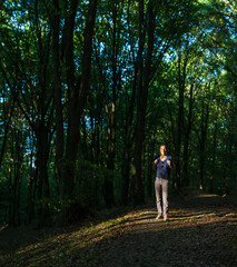 Fototapeta premium Young smiling woman with backpack standing in the woods