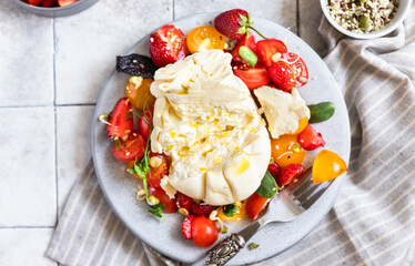 Salad with burrata cheese, cherry tomatoes and strawberry with microgreen and olive oil. Traditional Italian burrata cheese. Summer food. Healthy eating concept. Keto diet.