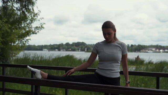 girl goes in for sports, does stretching in the park on the bridge