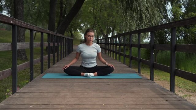 girl goes in for sports, does stretching in the park on the bridge