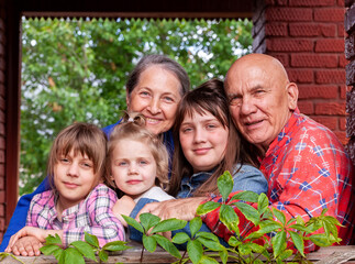 Portrait of elderly grandparents with three granddaughters on  porch of  village house.