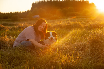 Beautiful woman walking out her dog in  sunset field