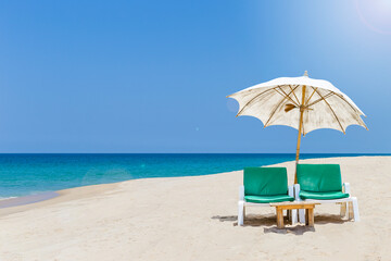 Tropical summer season, relaxing by the beach, beach chair under old umbrella on sandy beach, summer outdoor day light